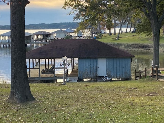 view of dock with a lawn and a water view