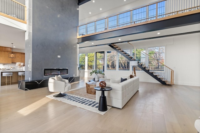 living room featuring a large fireplace, light hardwood / wood-style floors, sink, and a high ceiling