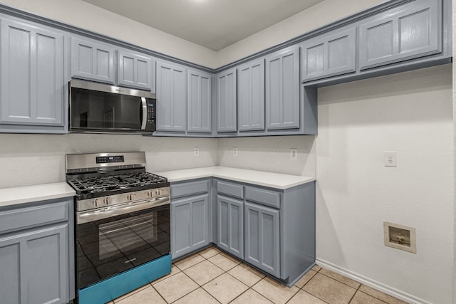 kitchen with gray cabinetry, light tile patterned floors, and stainless steel appliances