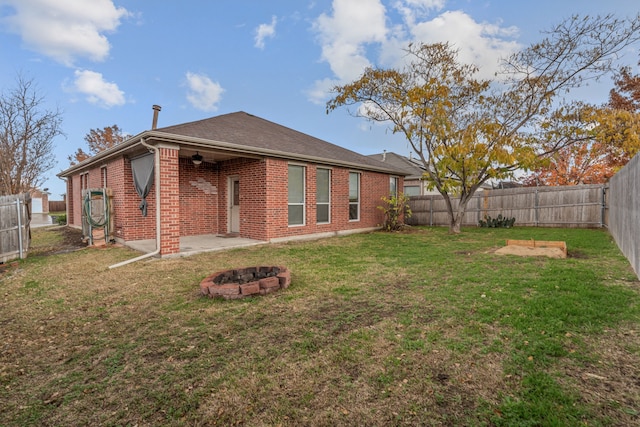 back of house featuring a fire pit, ceiling fan, and a yard