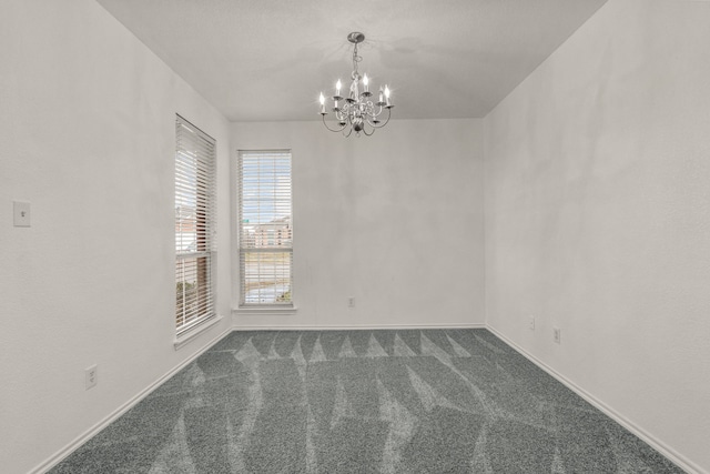 carpeted spare room with a notable chandelier