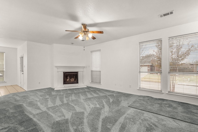 unfurnished living room with a wealth of natural light, ceiling fan, and light colored carpet