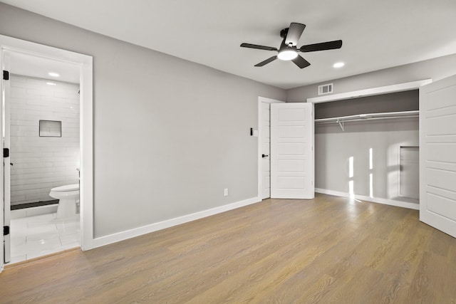 unfurnished bedroom featuring ensuite bath, a closet, light hardwood / wood-style flooring, and ceiling fan