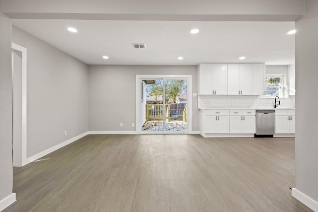 unfurnished living room with light hardwood / wood-style flooring, a wealth of natural light, and sink