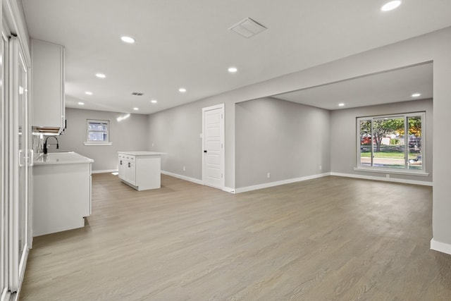 unfurnished living room with sink and light hardwood / wood-style flooring