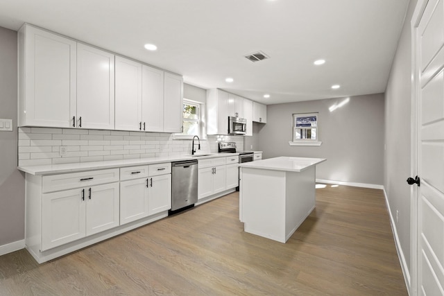 kitchen featuring a kitchen island, white cabinetry, stainless steel appliances, and light hardwood / wood-style flooring