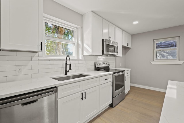 kitchen with light hardwood / wood-style flooring, stainless steel appliances, white cabinetry, and sink