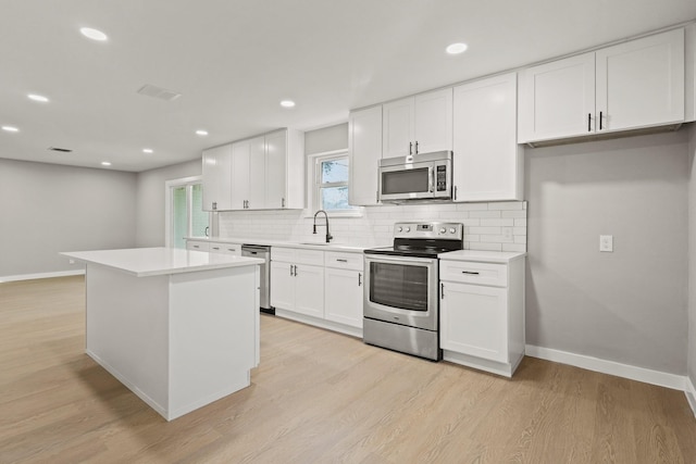 kitchen with light hardwood / wood-style flooring, white cabinets, and appliances with stainless steel finishes