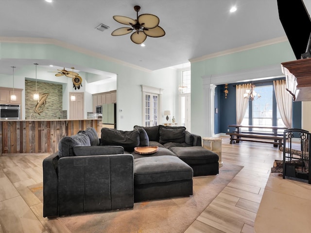 living room featuring ceiling fan with notable chandelier, plenty of natural light, and crown molding