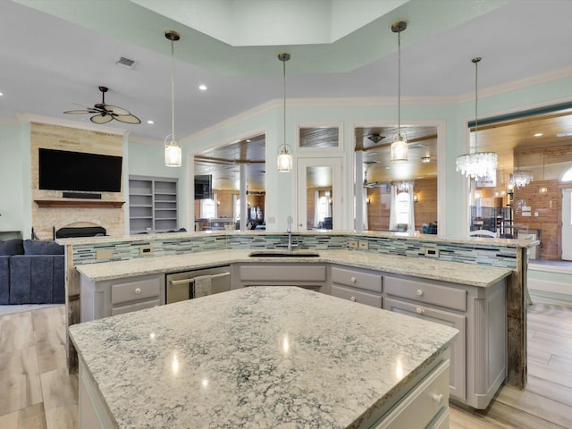 kitchen with light stone countertops, sink, a spacious island, and decorative light fixtures