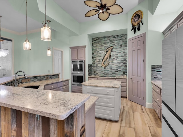 kitchen with gray cabinets, tasteful backsplash, decorative light fixtures, a kitchen island, and sink