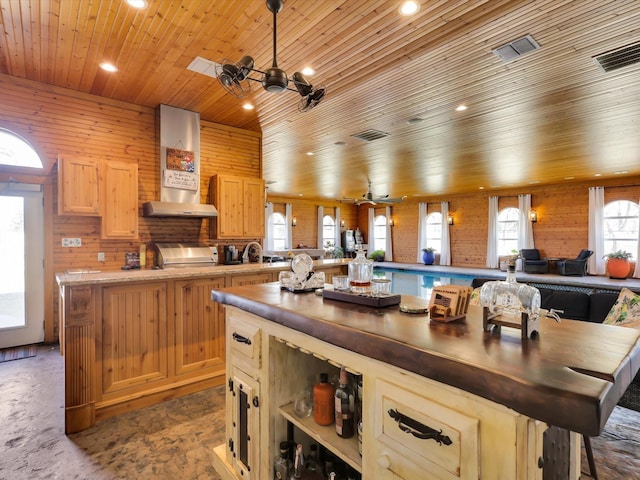 kitchen with ceiling fan, light brown cabinets, wall chimney exhaust hood, and wood ceiling