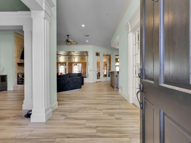 foyer entrance featuring ceiling fan, crown molding, and ornate columns