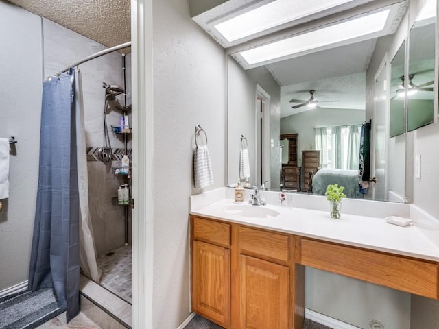 bathroom featuring ceiling fan, vanity, a skylight, and a shower with shower curtain