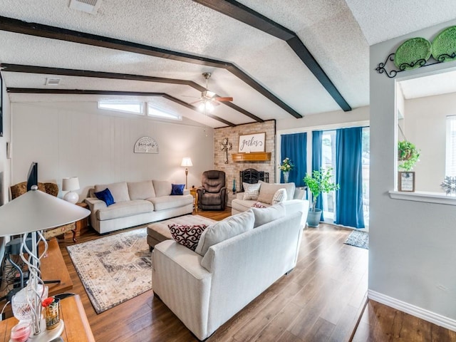 living room featuring plenty of natural light, a fireplace, a textured ceiling, and vaulted ceiling with beams