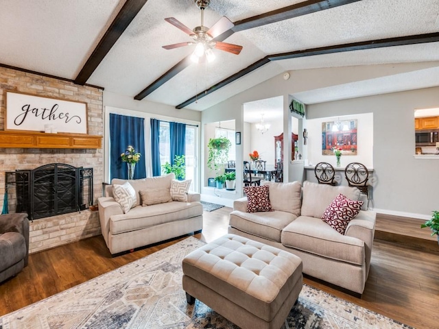 living room with dark wood-type flooring, a textured ceiling, a brick fireplace, and vaulted ceiling with beams