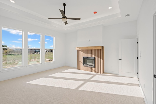 unfurnished living room featuring a tray ceiling, ceiling fan, and light colored carpet