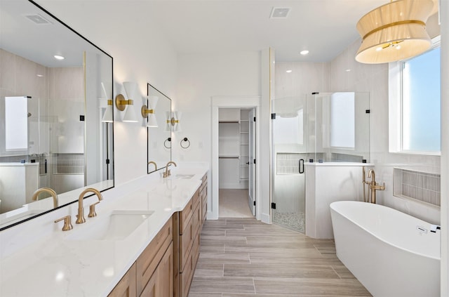 bathroom featuring hardwood / wood-style floors, vanity, tile walls, and plus walk in shower