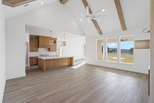 unfurnished living room featuring light hardwood / wood-style flooring, high vaulted ceiling, beamed ceiling, and sink