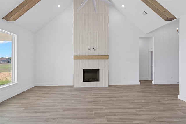 unfurnished living room with a wealth of natural light, a fireplace, high vaulted ceiling, and beamed ceiling