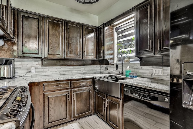 kitchen featuring sink, light stone counters, tasteful backsplash, dark brown cabinets, and black appliances