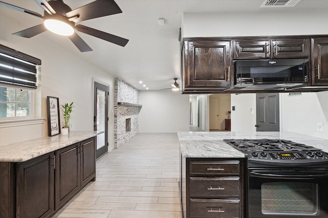 kitchen with dark brown cabinetry, ceiling fan, a fireplace, and black gas range