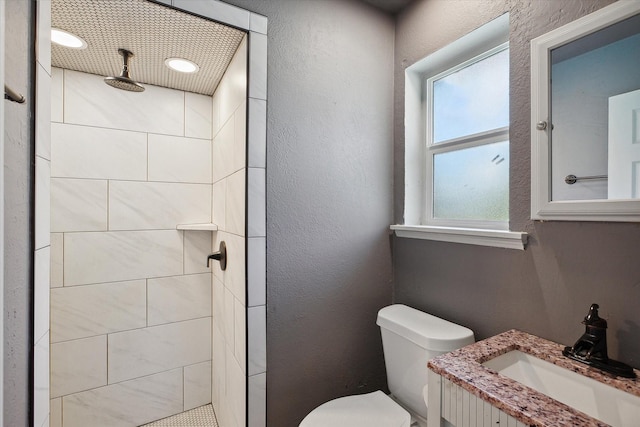 bathroom with vanity, a tile shower, and toilet