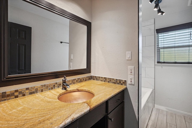 bathroom with tasteful backsplash, vanity, wood-type flooring, and  shower combination