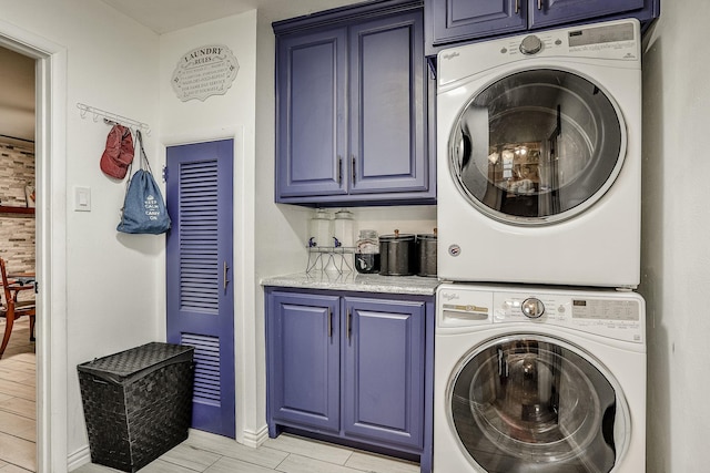 clothes washing area featuring cabinets and stacked washer / drying machine