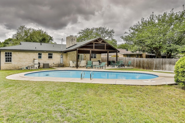 view of swimming pool with a yard, central AC unit, and a patio