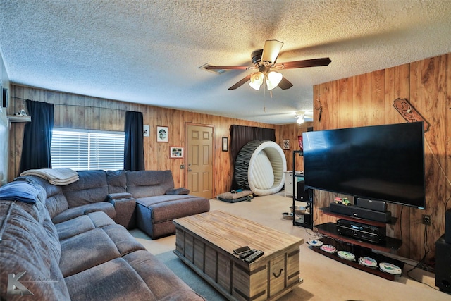 living room with a textured ceiling, light colored carpet, and wood walls