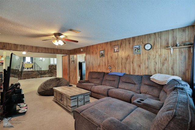 living room with ceiling fan, light colored carpet, a textured ceiling, and wooden walls