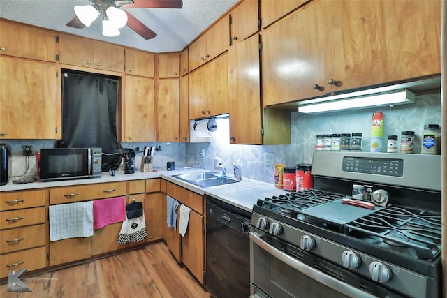 kitchen featuring backsplash, a textured ceiling, sink, black appliances, and light hardwood / wood-style floors