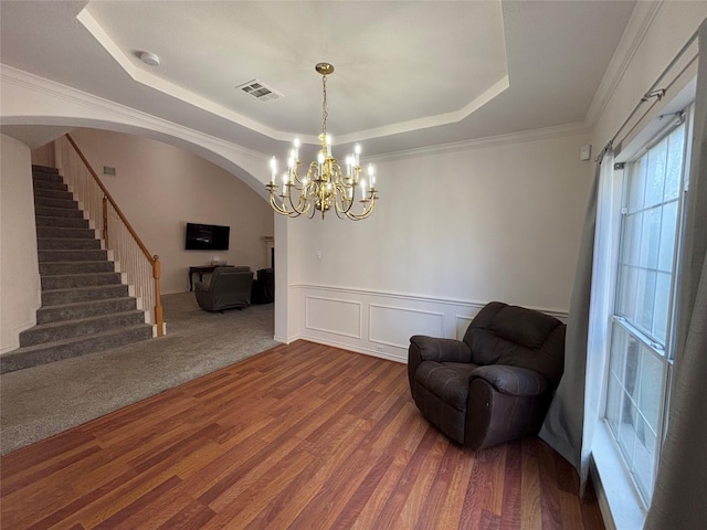 living area featuring crown molding, hardwood / wood-style flooring, a raised ceiling, and a chandelier