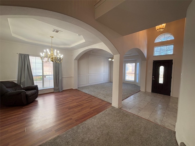 foyer featuring an inviting chandelier, light hardwood / wood-style flooring, and a raised ceiling