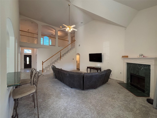 carpeted living room with ceiling fan, a premium fireplace, and high vaulted ceiling