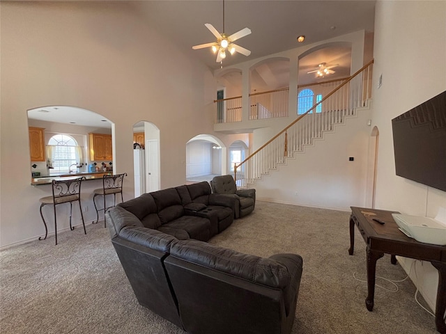 living room featuring light carpet, ceiling fan, and a high ceiling