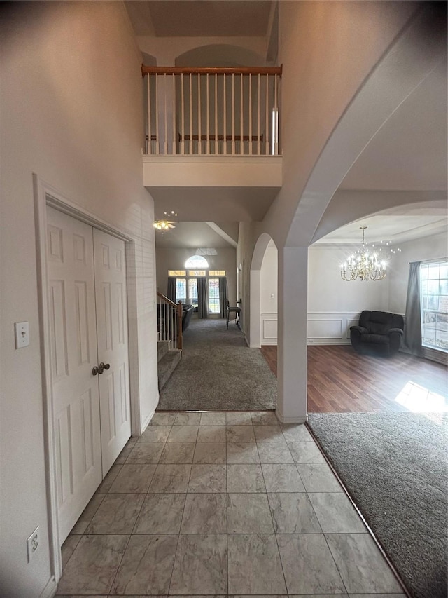 foyer featuring a towering ceiling, carpet floors, and a chandelier