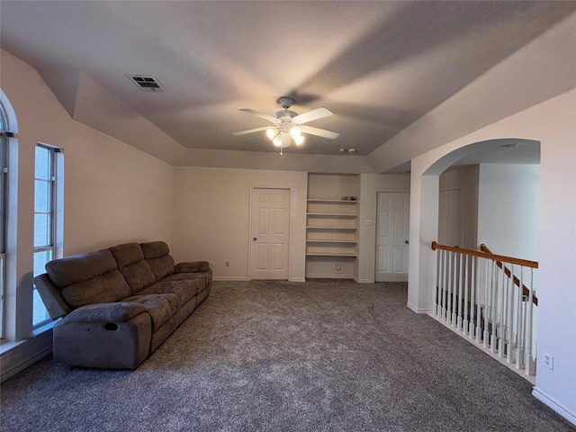 carpeted living room with built in shelves and ceiling fan