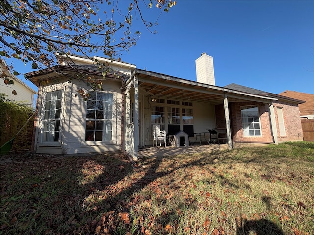 back of house with a patio and a lawn