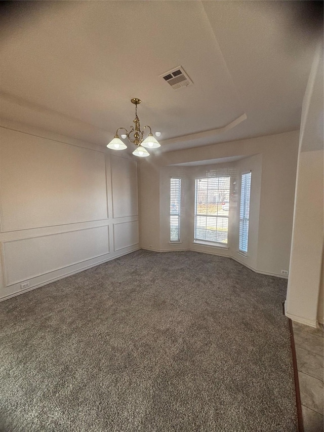 spare room with an inviting chandelier and dark colored carpet