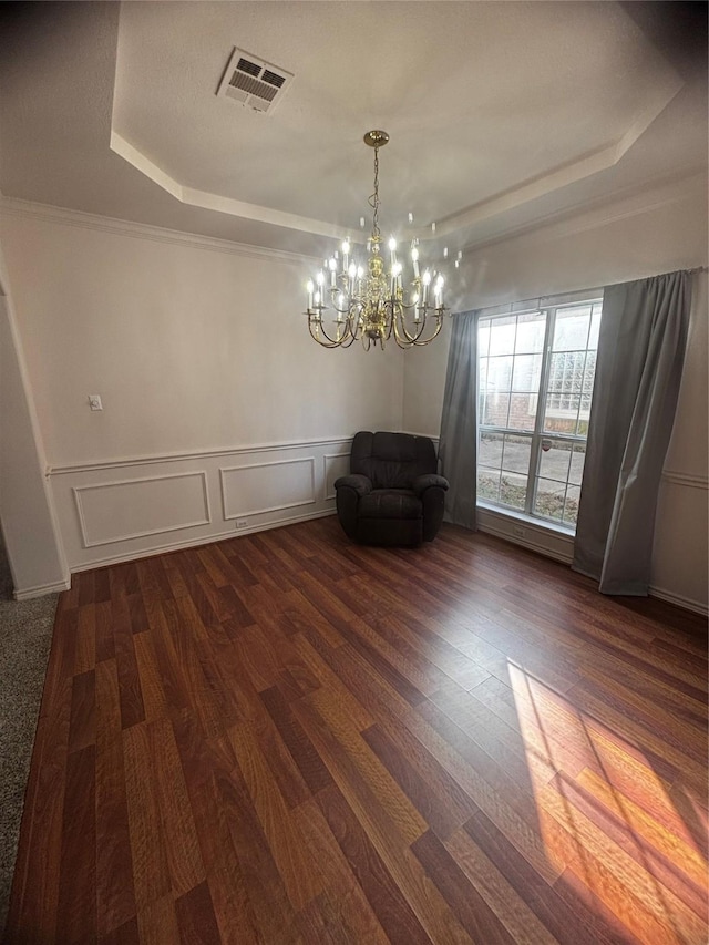 unfurnished dining area with an inviting chandelier, dark wood-type flooring, and a raised ceiling