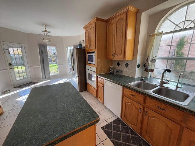 kitchen with light tile patterned flooring, white appliances, sink, and backsplash