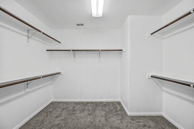 walk in closet featuring dark carpet