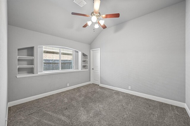 spare room with built in shelves, ceiling fan, carpet floors, and vaulted ceiling