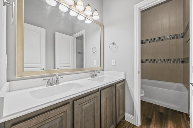 full bathroom featuring hardwood / wood-style floors, vanity, toilet, and tiled shower / bath