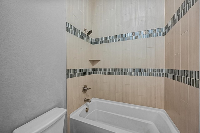 bathroom featuring tiled shower / bath combo and toilet