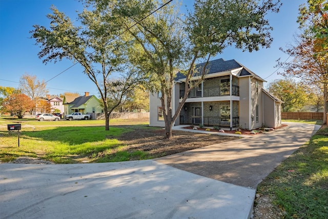 view of front of home featuring a balcony and a front yard