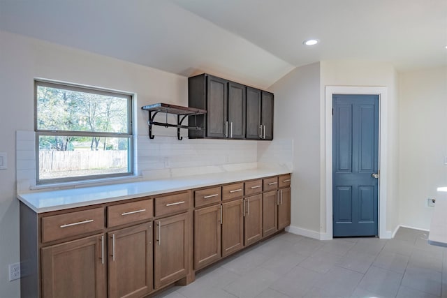 kitchen with decorative backsplash, light tile patterned floors, and vaulted ceiling