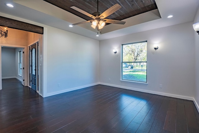 spare room featuring dark hardwood / wood-style floors, a raised ceiling, and ceiling fan